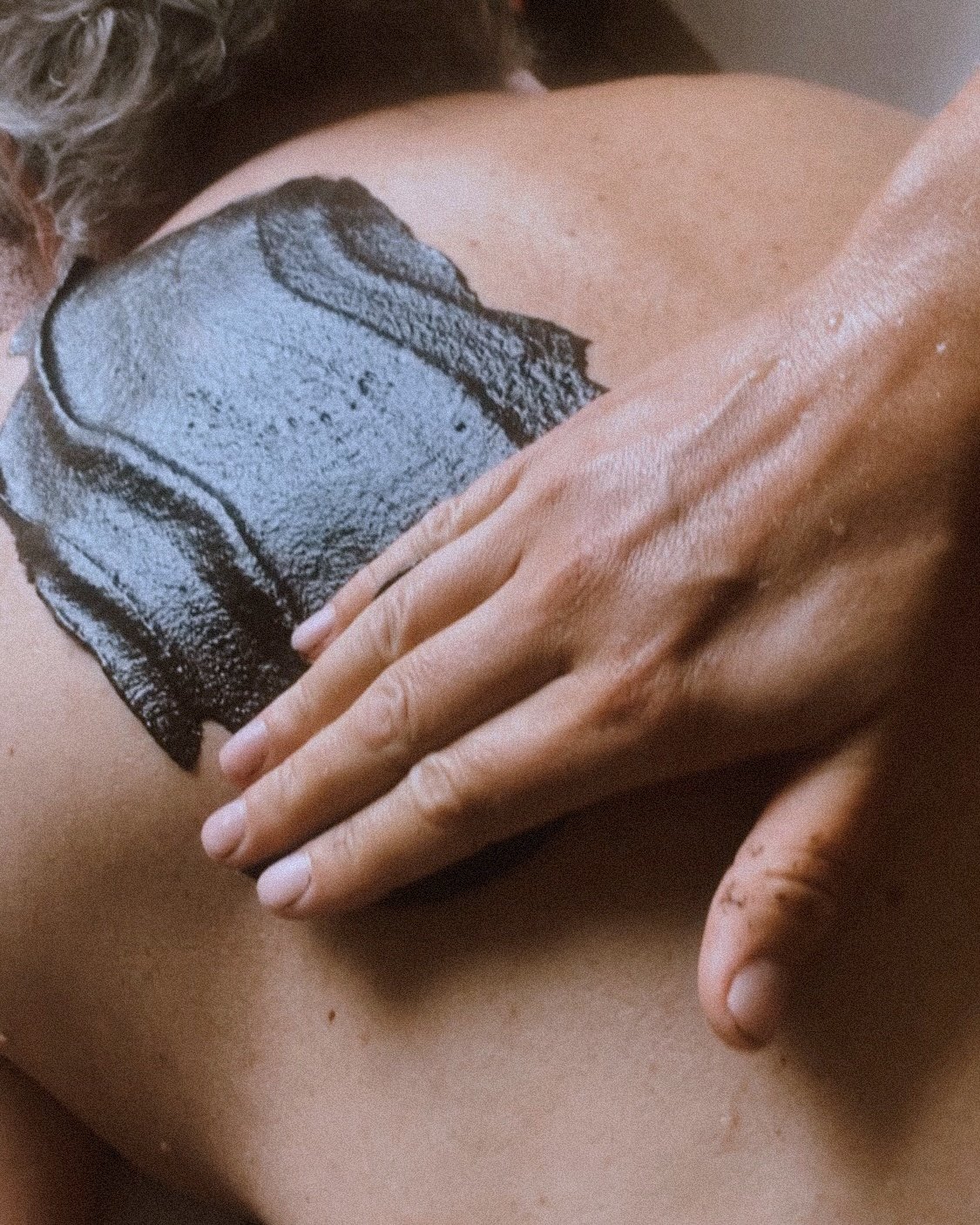 A person receiving a back massage with a towel on their back.
